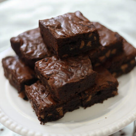 A batch of rich, fudgy chocolate brownies with crackled tops, cut into squares and displayed on a platter.